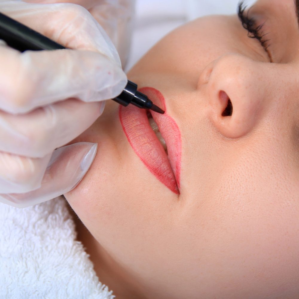 Young beautiful woman having permanent make-up (Tattoo)